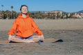 Smiling peaceful young woman in sportswear and headphones meditating with closed eyes while sitting in Lotus pose on Royalty Free Stock Photo