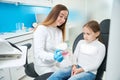 Cheerful stomatologist teaching pre-teen child tooth-brushing technique