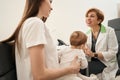 Friendly ophthalmologist giving primary consultation to young mother with infant