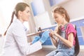 Smiling pediatrician and little girl patient holding stethoscope