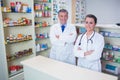 Smiling pharmacist and his trainee with arms crossed