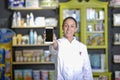 Smiling pharmacist woman showing a mobile phone