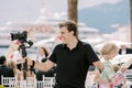 Smiling photographer taking pictures of a wedding ceremony while holding a digital camera in his hand on a stand Royalty Free Stock Photo