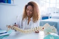 Smiling physiotherapist holding spine model