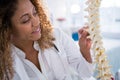 Smiling physiotherapist looking at spine model