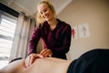 Smiling physiotherapist pressing shoulder of patient lying on massage bed in exercise studio.