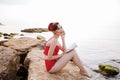 Smiling pin up girl reading book sitting on the rock Royalty Free Stock Photo
