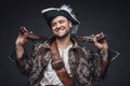 Smiling buccaneer with handguns against dark background