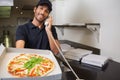 Smiling pizza delivery man taking an order over the phone showing a pizza Royalty Free Stock Photo