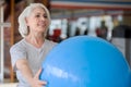 Smiling pleasant woman doing exercises with fit ball.