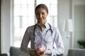 Smiling pleasant young female doctor holding piggybank in hands. Royalty Free Stock Photo