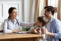 Smiling pleasant young female doctor stroking head of little patient. Royalty Free Stock Photo