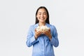 Smiling pleased asian girl enjoying day-off in bed with popcorn, eating and watching movies in pajamas, standing white