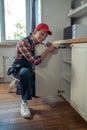 Cheerful serviceman repairing kitchen furniture in a client apartment