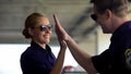 Smiling police teammates giving high-five to each other, coworking concept, team
