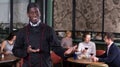 Smiling African American chef inviting to restaurant