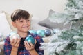 Smiling portrait child decorate the christmas tree with balls at home