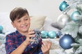 Smiling portrait child decorate the christmas tree with pine cone and balls at home