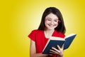 Smiling Portrait of a cute little schoolgirl loving to learn, holding with hands a book and wearing glasses Royalty Free Stock Photo