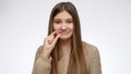 Smiling portrait of girl showing small or tiny gesture over white studio background. Royalty Free Stock Photo