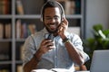 Smiling positive African American man wearing headphones using phone