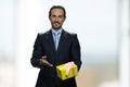 Smiling positive businessman is presenting yellow gift box.