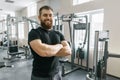 Smiling positive confident male personal instructor with arms crossed in fitness gym Royalty Free Stock Photo