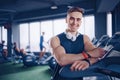 Smiling positive confident male personal instructor with arms crossed arms near treadmill at gym in fitness gym Royalty Free Stock Photo