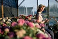 smiling nice female gardene writing in notebook in greenhouse, sit next to flowers Royalty Free Stock Photo