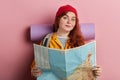 Smiling positive ginger tourist holding a map, making decision where to travel