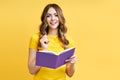 Smiling positive girl reading book on yellow background