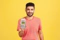 Smiling positive man with beard in striped t-shirt holding in hand pos contactless payment terminal, using paypass for purchases