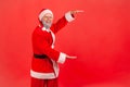 Smiling positive man pretending to be santa claus showing advertising area and looking at camera with smile, freespace for your