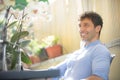 Smiling and positive man sitting outdoors. White Caucasian with tight blue shirt. Around him spring flowers, orchids. Strong Royalty Free Stock Photo