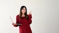 A smiling Asian female college student is pointing her finger up and holding her laptop Royalty Free Stock Photo