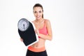 Smiling positive young fitness woman in sportwear holding weighing scale Royalty Free Stock Photo