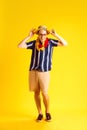 Smiling positive young man, tourist in casual clothes, sunglasses and straw hat posing against yellow studio background Royalty Free Stock Photo