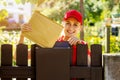 Smiling postman mail carrier inserting envelope into mailbox