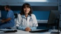 Smiling practitioner medic standing at desk in hospital office working after hours at health care treatment