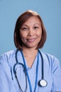 Smiling practitioner nurse wearing stethoscope and blue coat during medical appointment