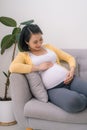 Smiling pregnant asian woman sitting on the sofa Royalty Free Stock Photo