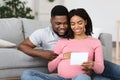 Smiling pregnant black couple holding white blank card Royalty Free Stock Photo