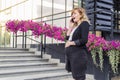 A smiling pregnant businesswoman in front of a modern building while talking on her mobile phone