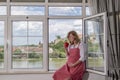 A pregnant caucasian woman sitting by the window with a cup of coffee or tea Royalty Free Stock Photo