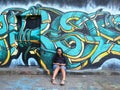 Smiling pregnant girl sitting by door with abstract street art