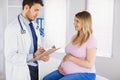 Smiling pregnant patient talking to doctor which is taking notes Royalty Free Stock Photo