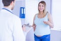 Smiling pregnant patient talking to doctor which is taking notes Royalty Free Stock Photo