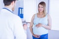 Smiling pregnant patient talking to doctor which is taking notes Royalty Free Stock Photo