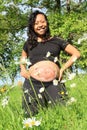 Smiling pregnant woman with drawing of baby on belly on meadow Royalty Free Stock Photo