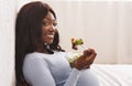 Smiling pregnant woman eating fresh salad on bed at home Royalty Free Stock Photo